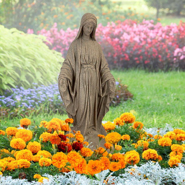 Full view of the Mother Mary Garden Statue resting in a garden setting, with colorful flowers surrounding it. The statue is constructed from durable resin for outdoor longevity.